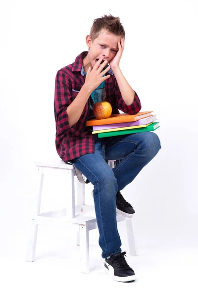 Uttråkad skolpojke med böcker — Stockfoto