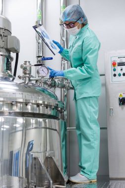 Fabrika içinde tank yakınındaki ayakta bilim adamı