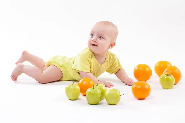 Улыбающийся младенец с яблоками и апельсинами — стоковое фото