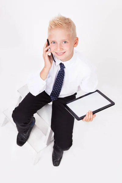 Skolan pojke i skjorta med surfplatta och telefon — Stockfoto