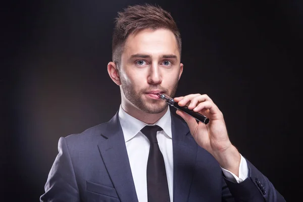 Jeune homme d'affaires fume cigarette électronique — Photo