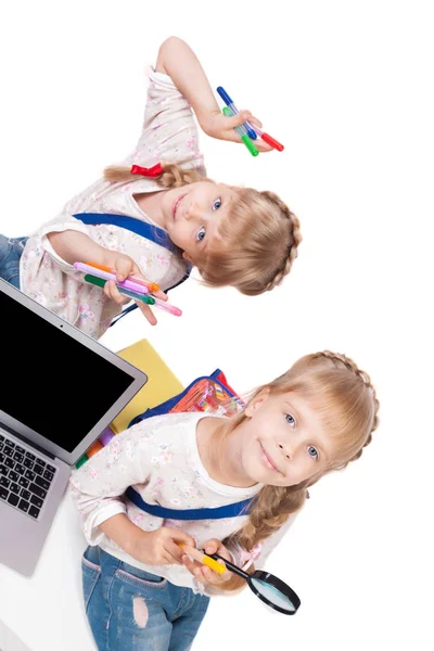 Девочки-близнецы с книгами и ноутбуком — стоковое фото