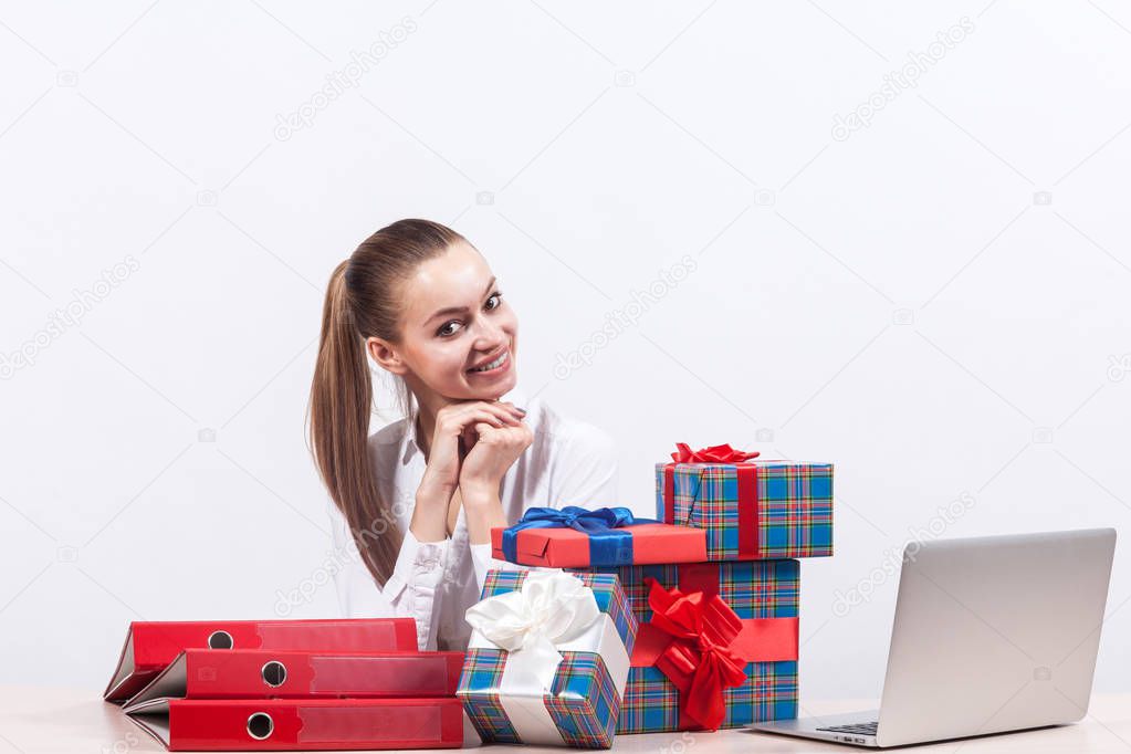 Businesswoman with gifts in office by laptop