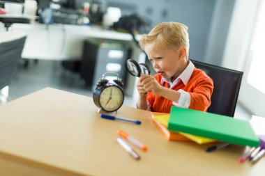 Büyüteç ile ofiste masasında genç çocuk