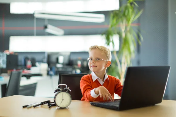 Милый мальчик в офисе пользуется компьютером. — стоковое фото