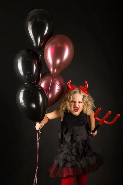 Little girl in devil costume with balloons