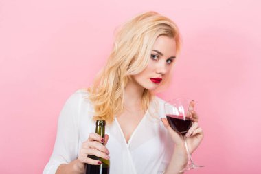 Güzel genç kadın ile cam ve pembe bir arka plan üzerinde kırmızı şarap şişe