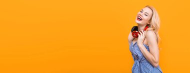 Sarı zemin üzerine kırmızı kulaklıklarla güzel şık bir genç kadın