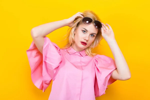 黄色の背景にポーズ ピンクのブラウスでスタイリッシュな若い女性の肖像画 — ストック写真