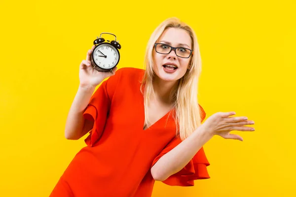 Emotional Young Woman Red Dress Holding Alarm Clock Yellow Background — Stock Photo, Image