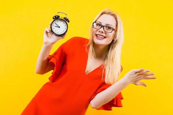 Emotional Young Woman Red Dress Holding Alarm Clock Yellow Background — Stock Photo, Image