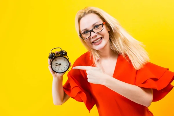 Emotional Young Woman Red Dress Holding Alarm Clock Yellow Background — Stock Photo, Image