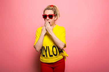 Parlak sarı tişört ve güneş gözlüğü pembe giyen genç ifade kadın