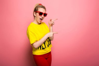 Parlak sarı tişört ve güneş gözlüğü pembe giyen genç ifade kadın
