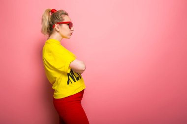 Parlak sarı tişört ve güneş gözlüğü pembe giyen genç ifade kadın