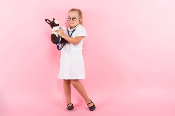 Милая Маленькая Девочка Медицинской Форме Стетоскопом Плюшевым Кроликом Розовом Фоне — стоковое фото