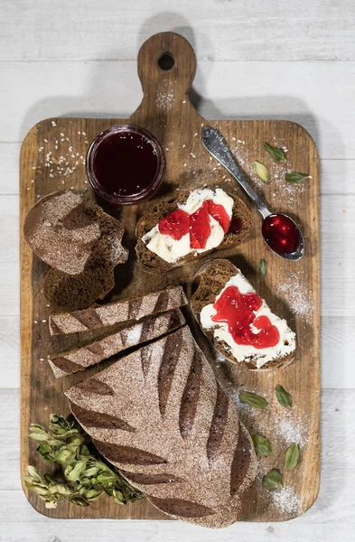 Fresh homemade bread with cream cheese and berry jam on cutting board