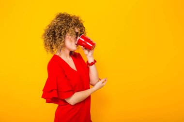 Kırmızı elbise içme içinde çekici genç kıvırcık saçlı kadın 