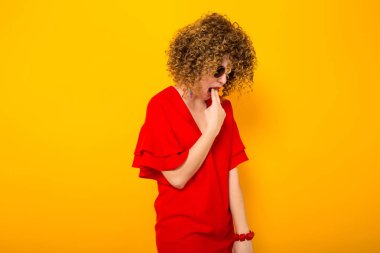 Çekici genç kıvırcık saçlı kadın kırmızı elbise ve hasta güneş gözlüğü