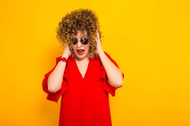 Çekici genç kıvırcık saçlı kadın kırmızı elbise ve çığlık güneş gözlüğü