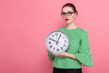 Gözlük, pembe arka plan duvar ckock tutan çekici genç esmer kadın 