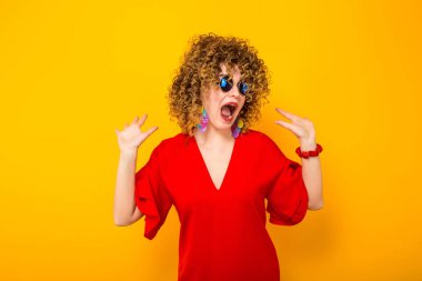 Heyecanlı çekici genç kıvırcık saçlı kadın kırmızı elbise ve güneş gözlüğü 