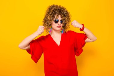 Kızgın genç kıvırcık saçlı kadın kırmızı elbise ve mücadele güneş gözlüğü