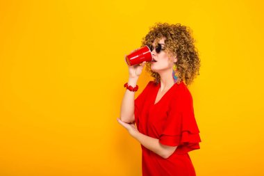 Kırmızı elbise içme içinde çekici genç kıvırcık saçlı kadın 