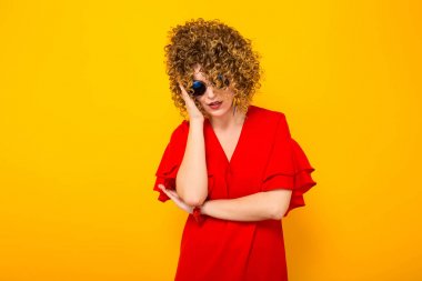 Sıkılmış çekici genç kıvırcık saçlı kadın kırmızı elbise ve güneş gözlüğü 