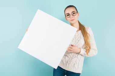 Mavi stüdyo arka planı boş afiş tutarak şık gözlük güzel kız 