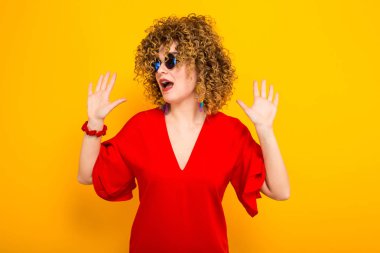 Heyecanlı çekici genç kıvırcık saçlı kadın kırmızı elbise ve güneş gözlüğü 