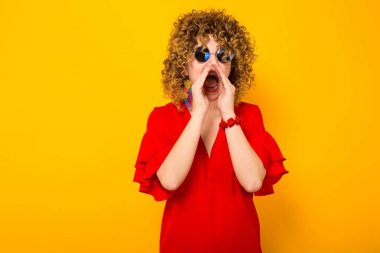 Çekici genç kıvırcık saçlı kadın kırmızı elbise ve çığlık güneş gözlüğü