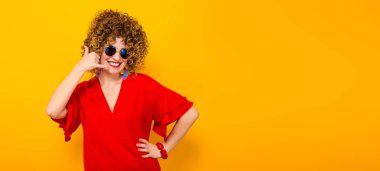 Çekici genç kıvırcık saçlı kadın kırmızı elbise ve güneş gözlüğü gösterilen ara beni jest