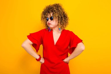 Kızgın çekici genç kıvırcık saçlı kadın kırmızı elbise ve güneş gözlüğü 