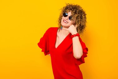 Çekici genç kıvırcık saçlı kadın kırmızı elbise ve güneş gözlüğü gösterilen ara beni jest