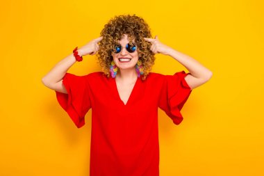 Çekici genç kıvırcık saçlı kadın kırmızı elbise ve onun kafasına işaret güneş gözlüğü