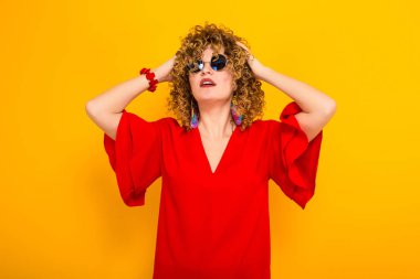 Çekici genç kıvırcık saçlı kadın kırmızı elbise ve kafasına elele güneş gözlüğü 