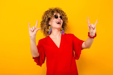 Duvar saati tutan Kırmızı elbiseli çekici genç kıvırcık saçlı kadın