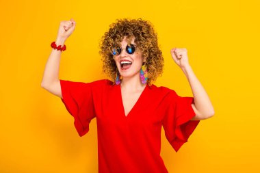 Çekici genç kıvırcık saçlı kadın kırmızı elbise ve kutlama güneş gözlüğü