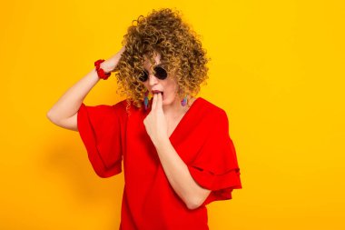 Çekici genç kıvırcık saçlı kadın kırmızı elbise ve hasta güneş gözlüğü