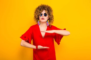 Çekici genç kıvırcık saçlı kadın kırmızı elbise ve boyutu gösteren güneş gözlüğü