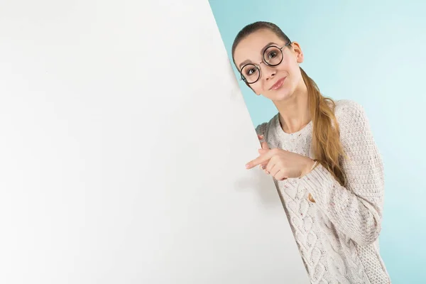 ブルー スタジオの背景の空白のバナーを保持しているスタイリッシュな眼鏡でかわいい女の子 — ストック写真