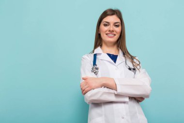 Kamera karşısına mavi arka plan, seyir stetoskop ile kendine güvenen genç bir kadın doktor 