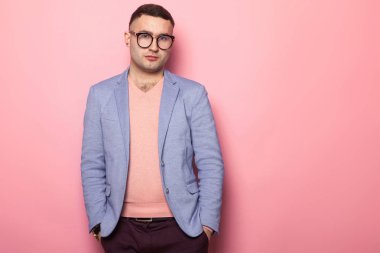 Mavi ceket ceplerinde pembe bir arka plan üzerinde el ele tutuşarak yakışıklı genç adam 