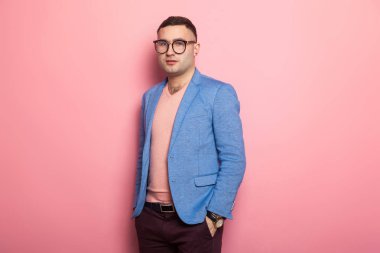 Mavi ceket ceplerinde pembe bir arka plan üzerinde el ele tutuşarak yakışıklı genç adam 