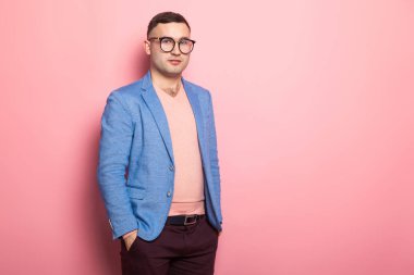 Mavi ceket ceplerinde pembe bir arka plan üzerinde el ele tutuşarak yakışıklı genç adam 