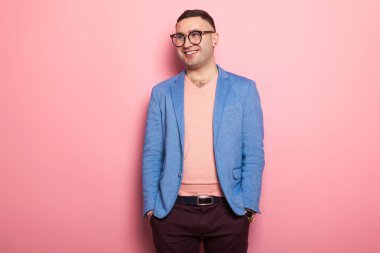 Mavi ceket ceplerinde pembe bir arka plan üzerinde el ele tutuşarak yakışıklı genç adam 