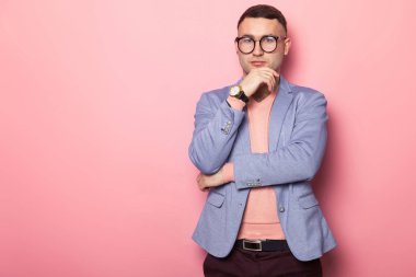 Şık gözlük ve mavi ceket ve kameraya poz pembe studio arka planı süre seyir yakışıklı genç 