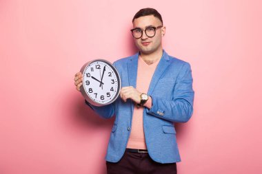 Duvar saati pembe studio arka planda tutan yakışıklı genç 