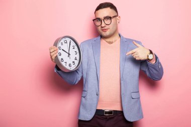 Zamana karşı pembe studio arka plan gösteren yakışıklı genç 